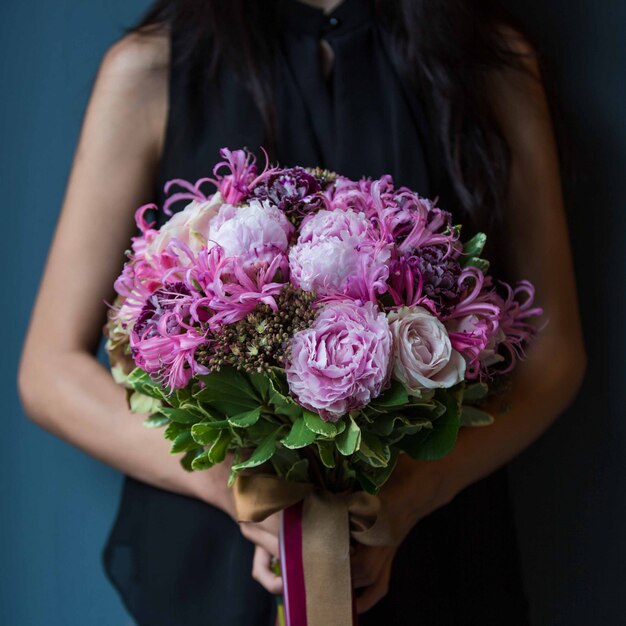 Uma garota segurando um buquê de tipos de flores roxas com as duas mãos
