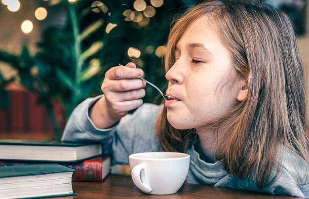 Uma garotinha gosta de chá enquanto está sentado em um café