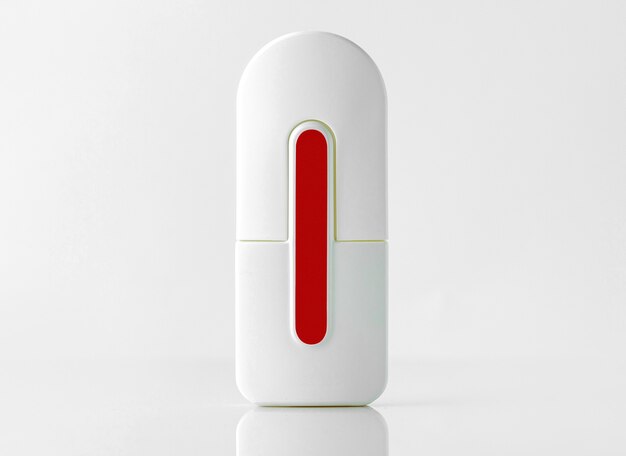 Uma garrafa de vista frontal com fragrância branca e vermelha projetada na parede branca