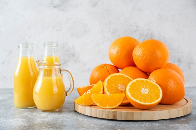 Uma jarra de vidro de suco com frutas frescas de laranja na mesa de pedra.