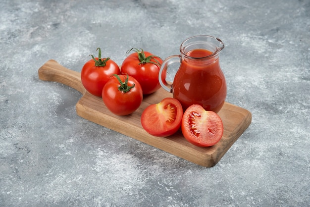 Uma jarra de vidro de suco com tomates frescos.