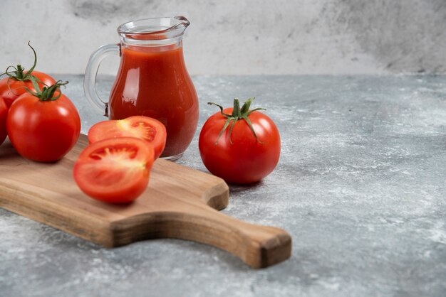 Uma jarra de vidro de suco com tomates frescos.