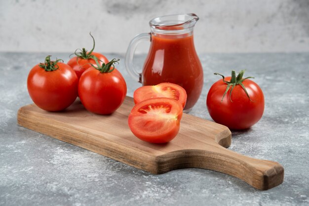 Uma jarra de vidro de suco com tomates frescos.