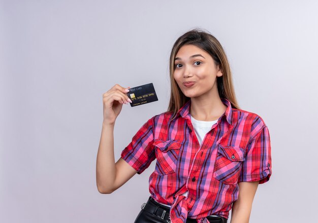 Uma jovem adorável e doce em uma camisa xadrez mostrando cartão de crédito