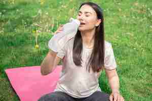 Foto grátis uma jovem bebendo água depois de se exercitar ao ar livre