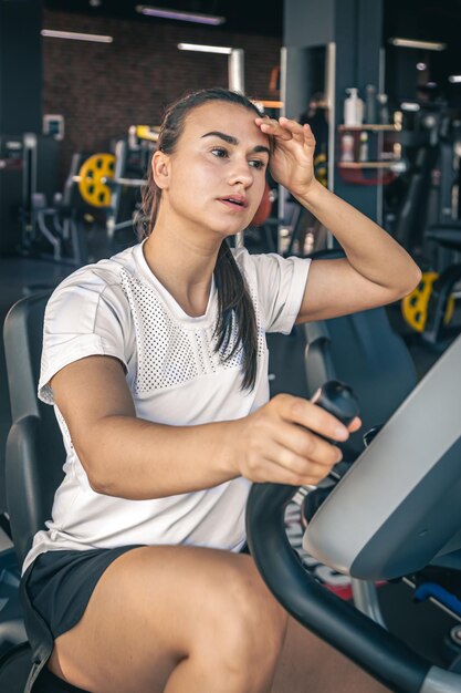 Uma jovem cansada após treino intenso na bicicleta ergométrica na academia