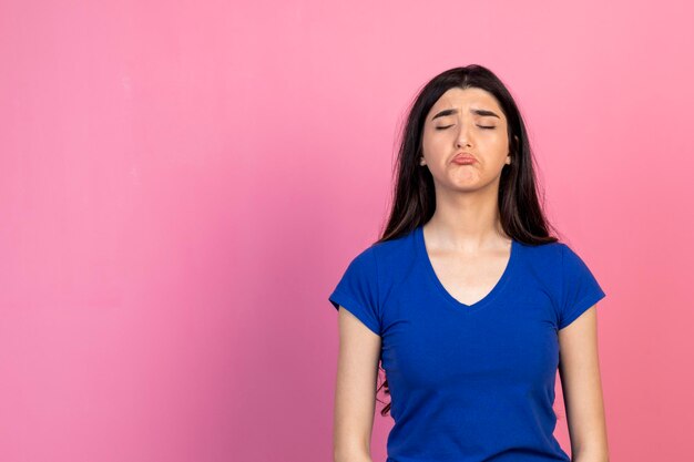 Uma jovem chateada em pé no fundo rosa Foto de alta qualidade