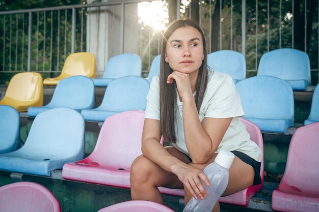 Foto grátis uma jovem com uma garrafa de água depois de treinar no estádio