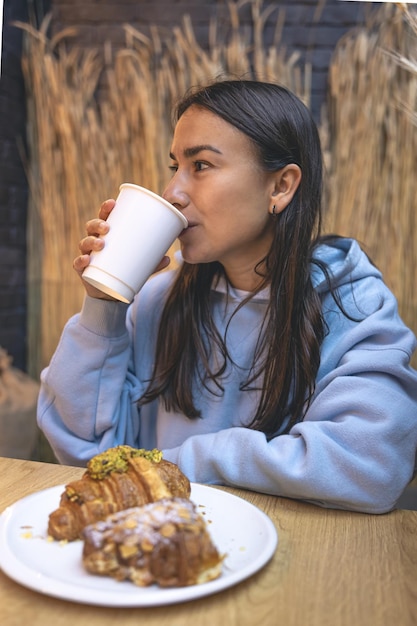 Uma jovem come croissants com café em um café