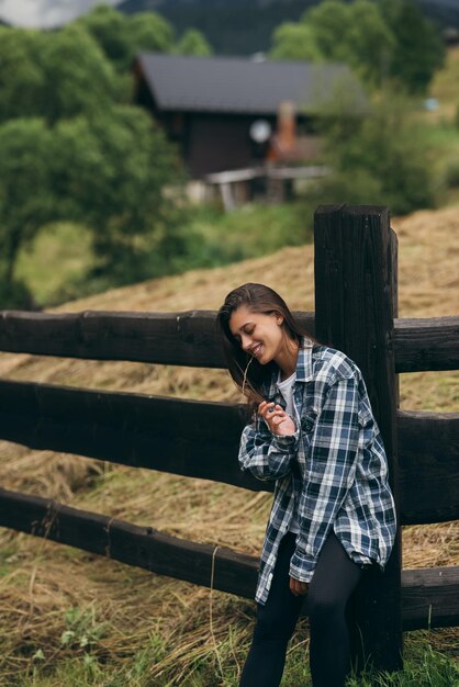 Uma jovem e atraente mulher caucasiana fica perto de uma cerca