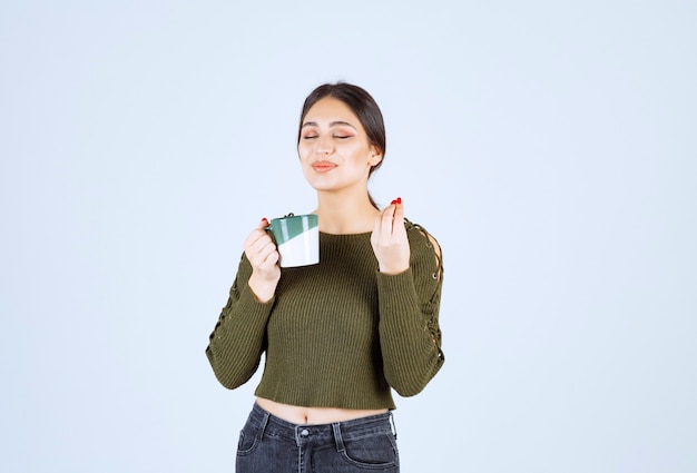 Uma jovem e bonita modelo tomando uma xícara de chá quente