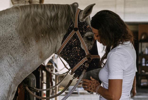 Uma jovem e um cavalo, sentimentos, cuidados, carinho, ternura, uma mulher abraça e beija um cavalo. Feche de jovem feliz abraçando seu cavalo.