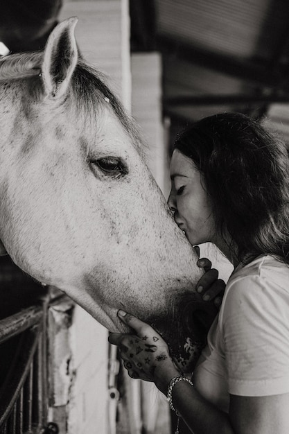Uma jovem e um cavalo, sentimentos, cuidados, carinho, ternura, uma mulher abraça e beija um cavalo. Feche de jovem feliz abraçando seu cavalo.