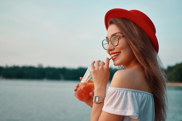 Uma jovem elegante, tomar uma bebida refrescante enquanto caminhava