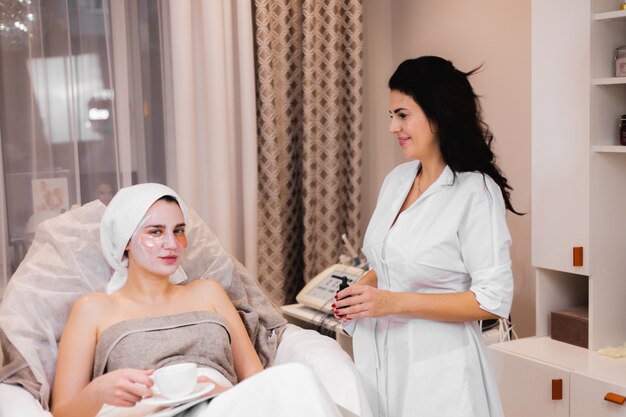 Uma jovem em um salão de beleza em um consultório de cosmetologia deitada na cama relaxando com uma máscara