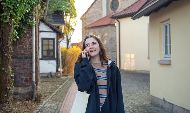 Uma jovem está falando ao telefone em uma caminhada na cidade