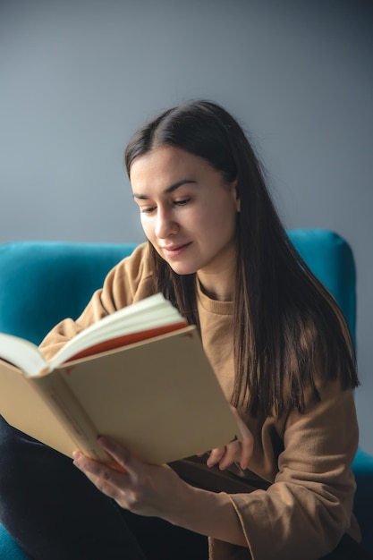 Foto grátis uma jovem está lendo um livro enquanto está sentada em uma cadeira