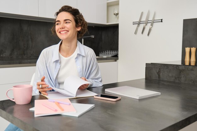 Uma jovem estudante feliz a fazer os trabalhos de casa, a escrever no diário, a sorrir e a parecer feliz.