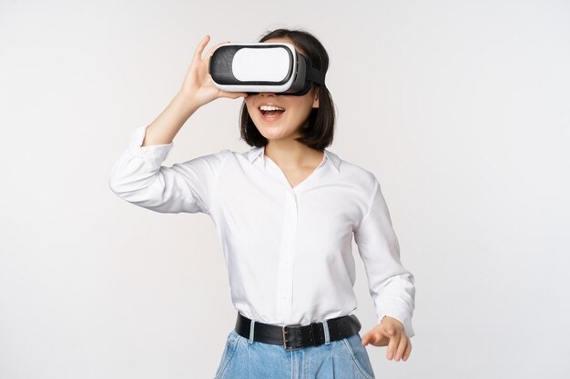 Uma jovem excitada entra em realidade virtual em seus óculos Garota asiática usando fone de ouvido vr sobre fundo branco