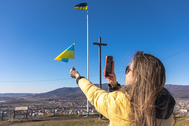 Uma jovem fotografa a bandeira da ucrânia contra o pano de fundo da cidade