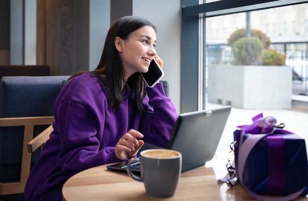 Uma jovem freelancer em um café com uma xícara de café e uma caixa de presente