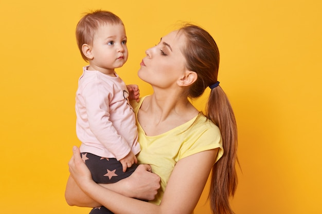 Uma jovem mãe carinhosa tenta acalmar a filha que chora.