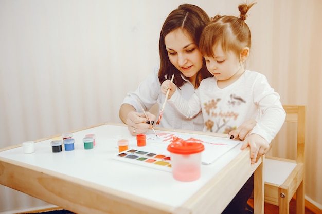 Uma jovem mãe, juntamente com sua filha pinta no papel