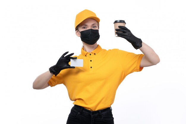 Uma jovem mensageira com uniforme amarelo, luvas pretas e máscara preta, segurando uma xícara de café e um cartão branco