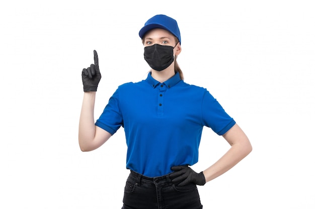 Uma jovem mensageira com uniforme azul, luvas pretas e máscara preta, posando com as mãos