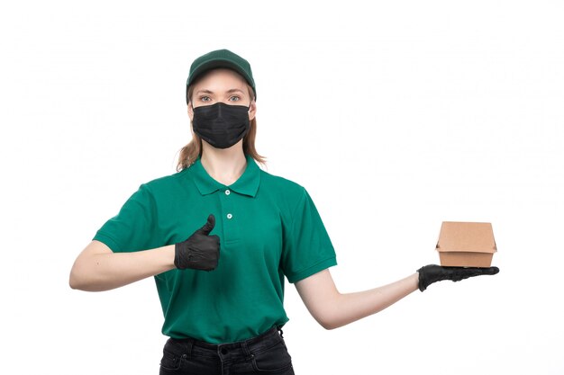 Uma jovem mensageira com uniforme verde, luvas pretas e máscara preta, segurando um pacote de entrega de comida