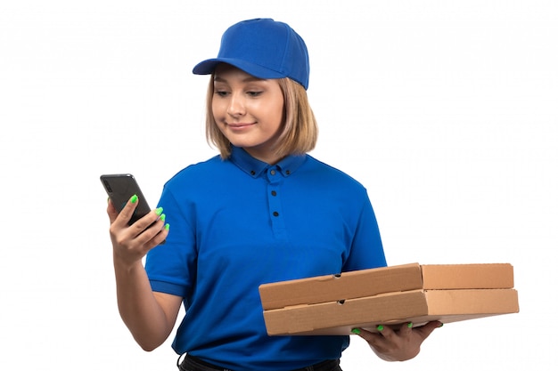 Uma jovem mensageira de uniforme azul segurando um telefone e pacotes de entrega de comida