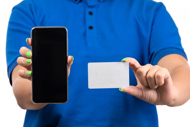 Uma jovem mensageira de uniforme azul segurando um telefone e um cartão branco de frente