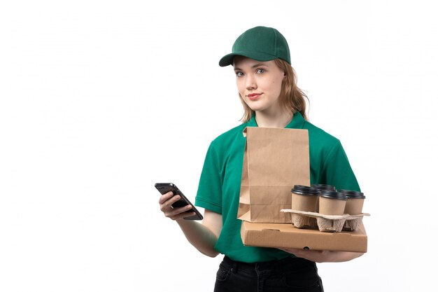 Uma jovem mensageira de uniforme verde, sorrindo, segurando pacotes de xícaras de café e usando um telefone, vista frontal