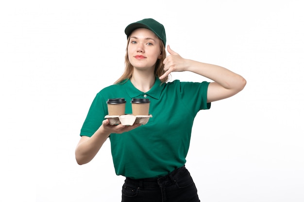 Uma jovem mensageira de uniforme verde, sorrindo, segurando xícaras de café e pedindo para ligar, vista frontal