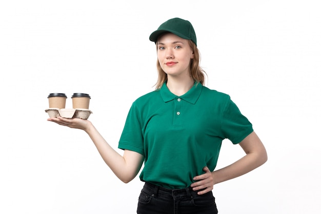 Foto grátis uma jovem mensageira de uniforme verde, sorrindo, segurando xícaras de café