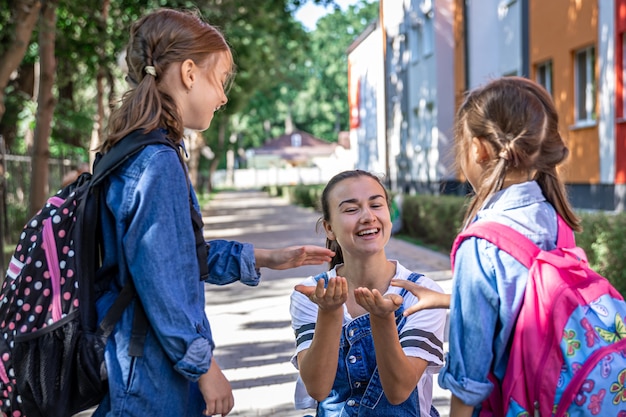 Uma jovem moralmente apóia as filhas de mãos dadas, incentiva os filhos, acompanha os alunos à escola.