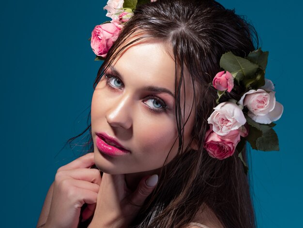 Uma jovem mulher bonita com flores rosas no cabelo molhado retrato de uma bela morena com perf ... Foto Premium