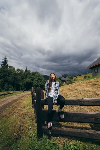 Uma jovem mulher branca e atraente sentada em uma cerca