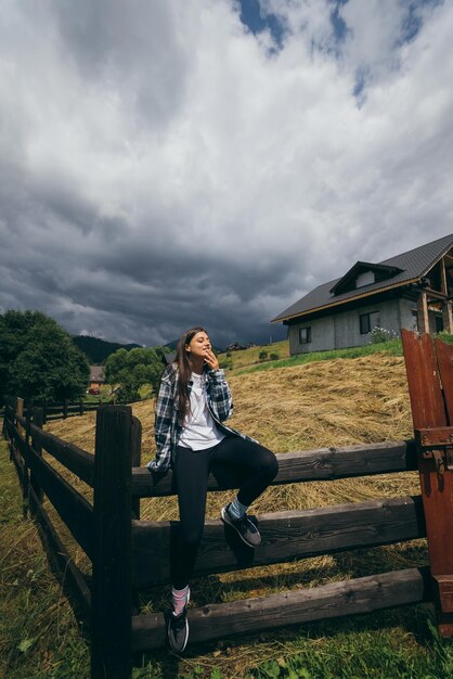 Uma jovem mulher branca e atraente sentada em uma cerca