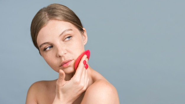 Foto grátis uma jovem mulher caucasiana está fazendo uma massagem facial usando esfregador de rosto