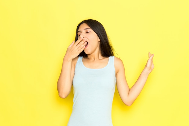 Uma jovem mulher de camisa azul posando e espirrando de frente para o modelo de pose de garota com fundo amarelo