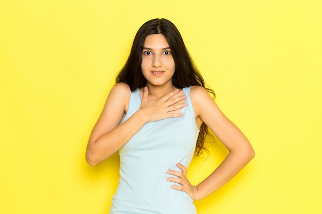 Foto grátis uma jovem mulher de camisa azul, vista frontal, posando no fundo amarelo.