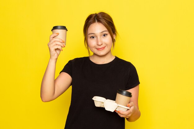 Uma jovem mulher de vestido preto segurando xícaras de café com um sorriso no rosto amarelo