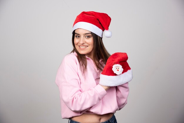 Uma jovem mulher segurando chapéus de Papai Noel e posando.