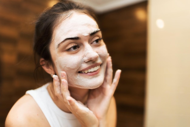 Foto grátis uma jovem mulher sorridente caucasiana está fazendo uma máscara facial