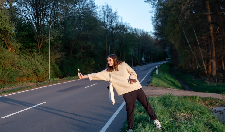 Foto grátis uma jovem perto da estrada para o carro pedindo carona