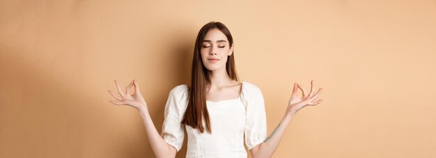 Uma jovem relaxada meditando de mãos dadas em pose de yoga zen e fechando os olhos sente paz e sorri