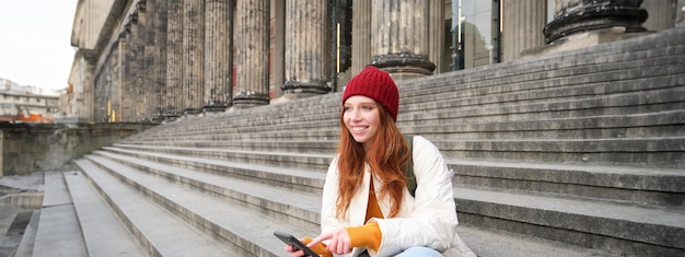 Uma jovem ruiva estilosa falando em um aplicativo de celular usando um aplicativo de mídia social procurando