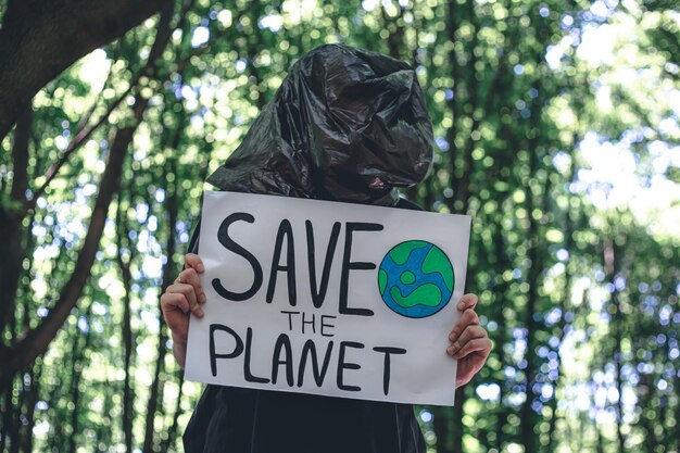 Foto grátis uma jovem segura um cartaz com uma chamada para salvar o planeta