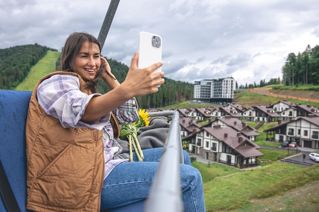 Uma jovem tira uma selfie em um funicular nas montanhas
